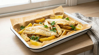 Tray of baked flathead fillets and potato wedges with lemon and parsley