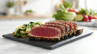 Sliced seared tuna steak with sesame seeds and Asian greens